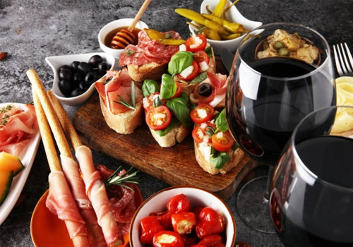 dos copas de vino tinto acompañando a una picada.